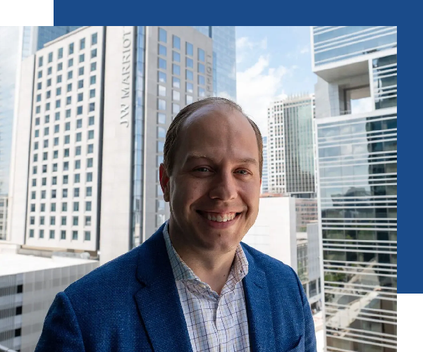 A man in a blue suit standing next to some buildings.