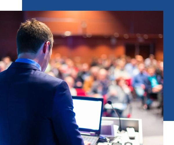 A man in front of an audience using his laptop.